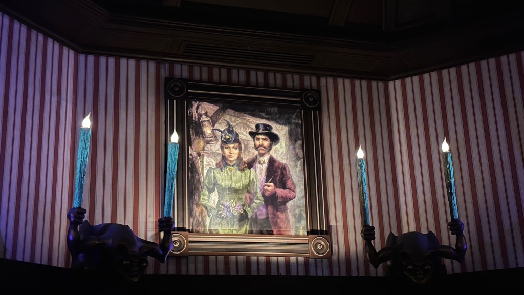 Framed picture of woman and man wearing Western clothing next to striped wallpaper inside Phantom Manor at Disneyland Paris