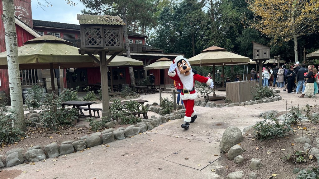 Goofy in a Santa outfit walking along in Frontierland in Disneyland Paris