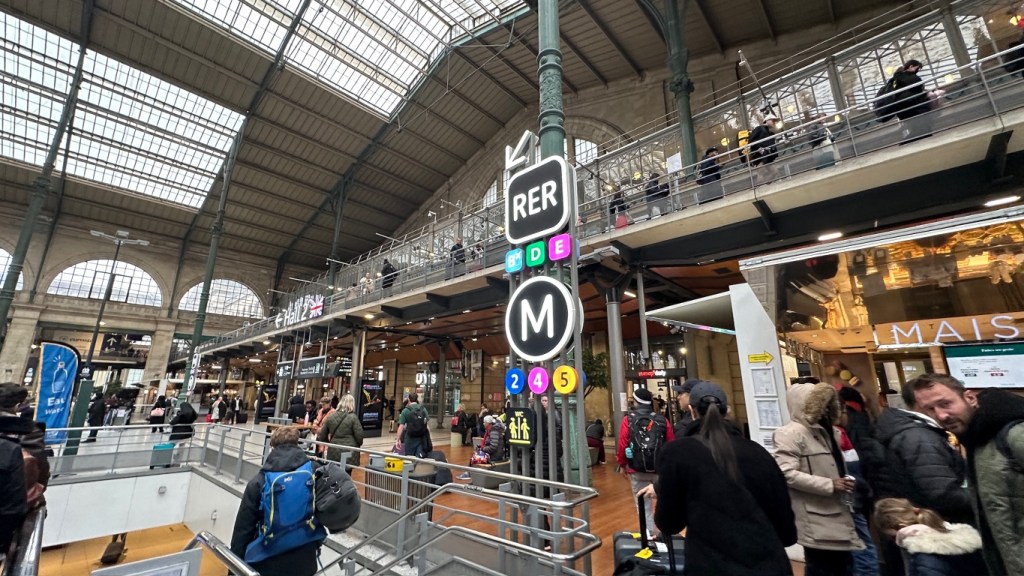 Concourse at Gare du Nord station with sign down stairs and escalators for RER B, D and E and M 2, 4, 5