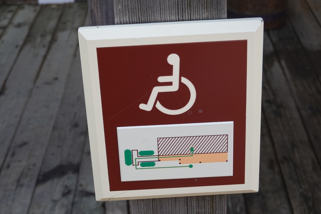 Wheelchair sign with directions to an accessible entrance in Hotel Cheyenne at Disneyland Paris